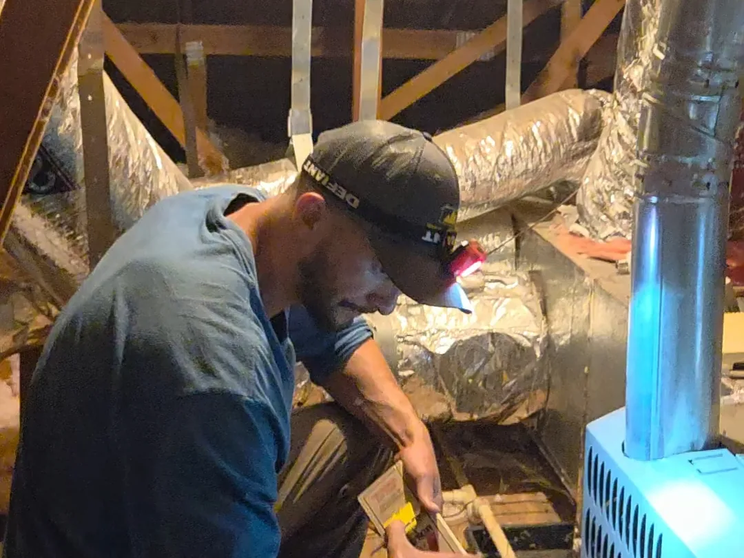Technician inspecting an attic beside ductwork for rodent activity