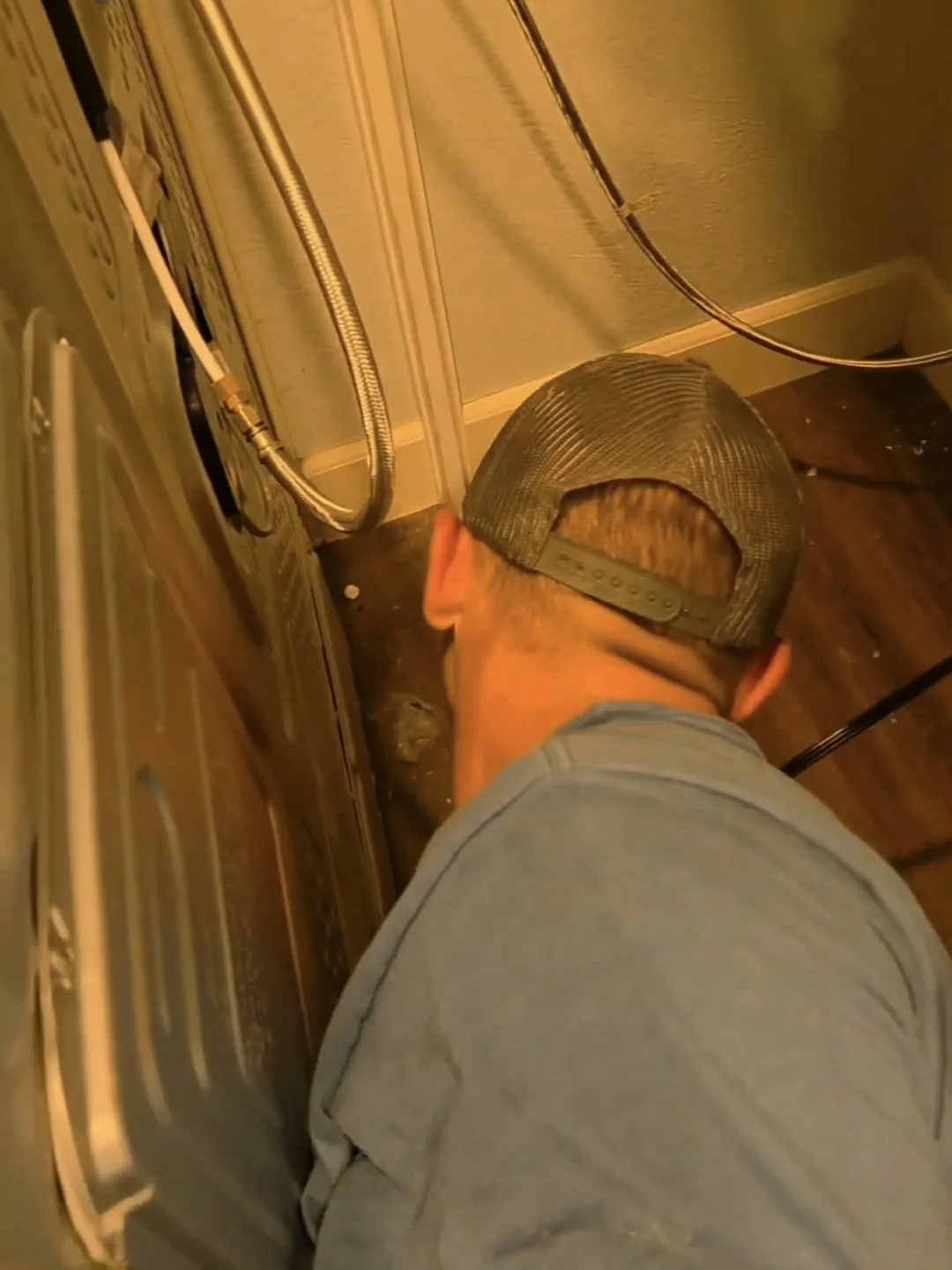 Technician inspecting behind a kitchen appliance for cockroach harbourage