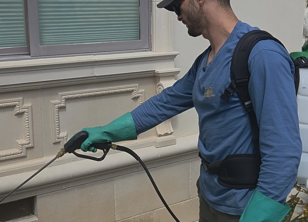 Summit Pest Control technician treating along a home foundation line