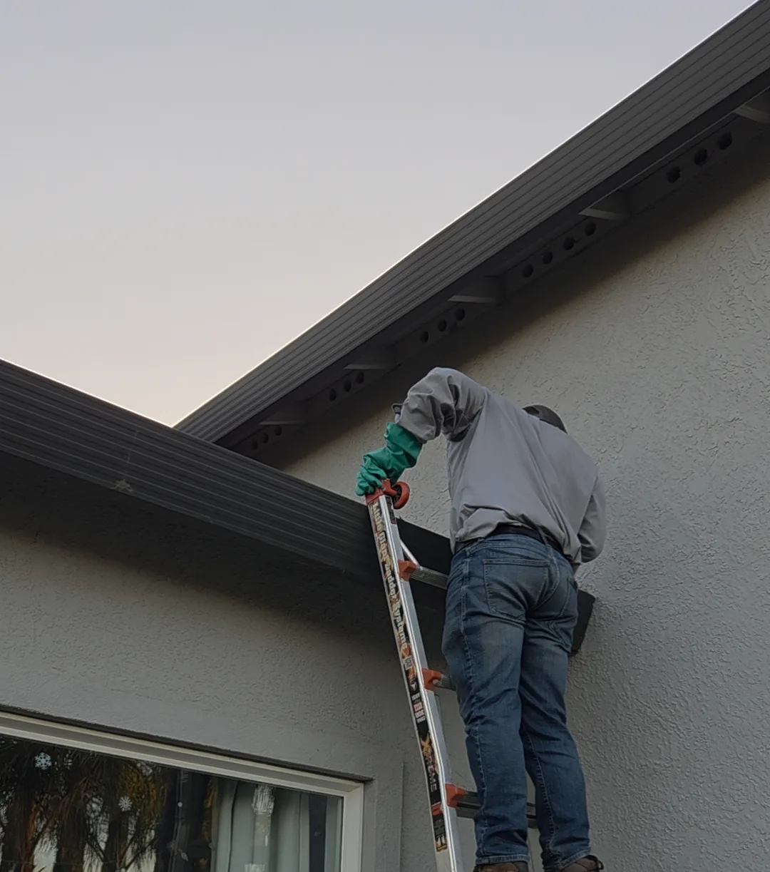 Technician working from a ladder at a home's roofline