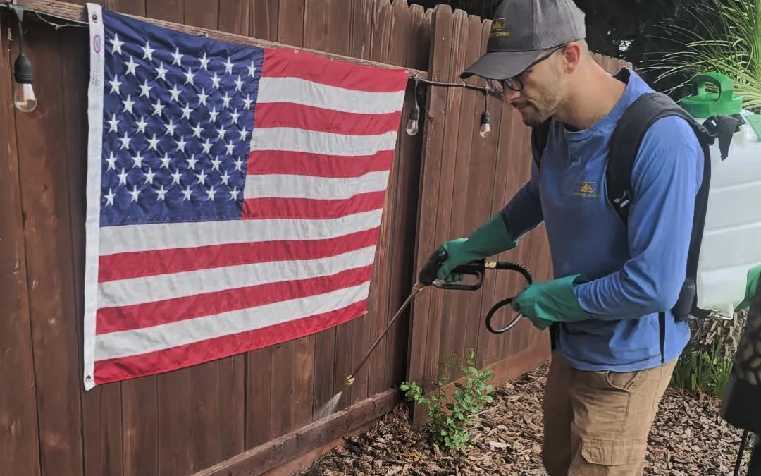 Summit Pest Control technician treating a fence line and mulch bed