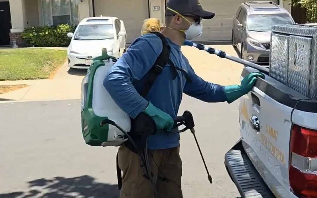 Summit Pest Control technician preparing a backpack sprayer at the service truck